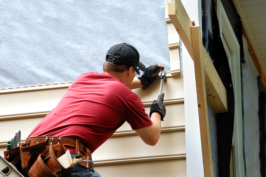 Greenwich siding contractor installs siding to his home. He is holding a hammer and wearing a tool belt.